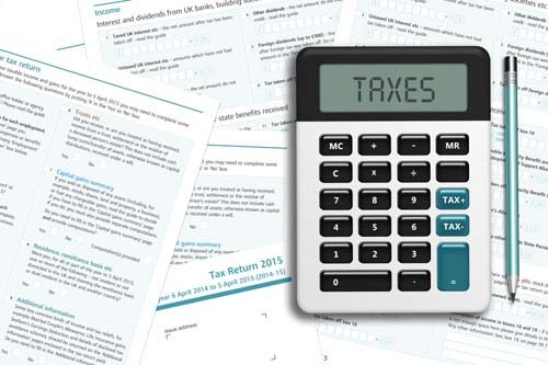 UK tax form with calculator lying on wooden desk